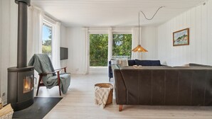 Een gezellige woonkamer met een open haard, een bank, een fauteuil en een televisie.