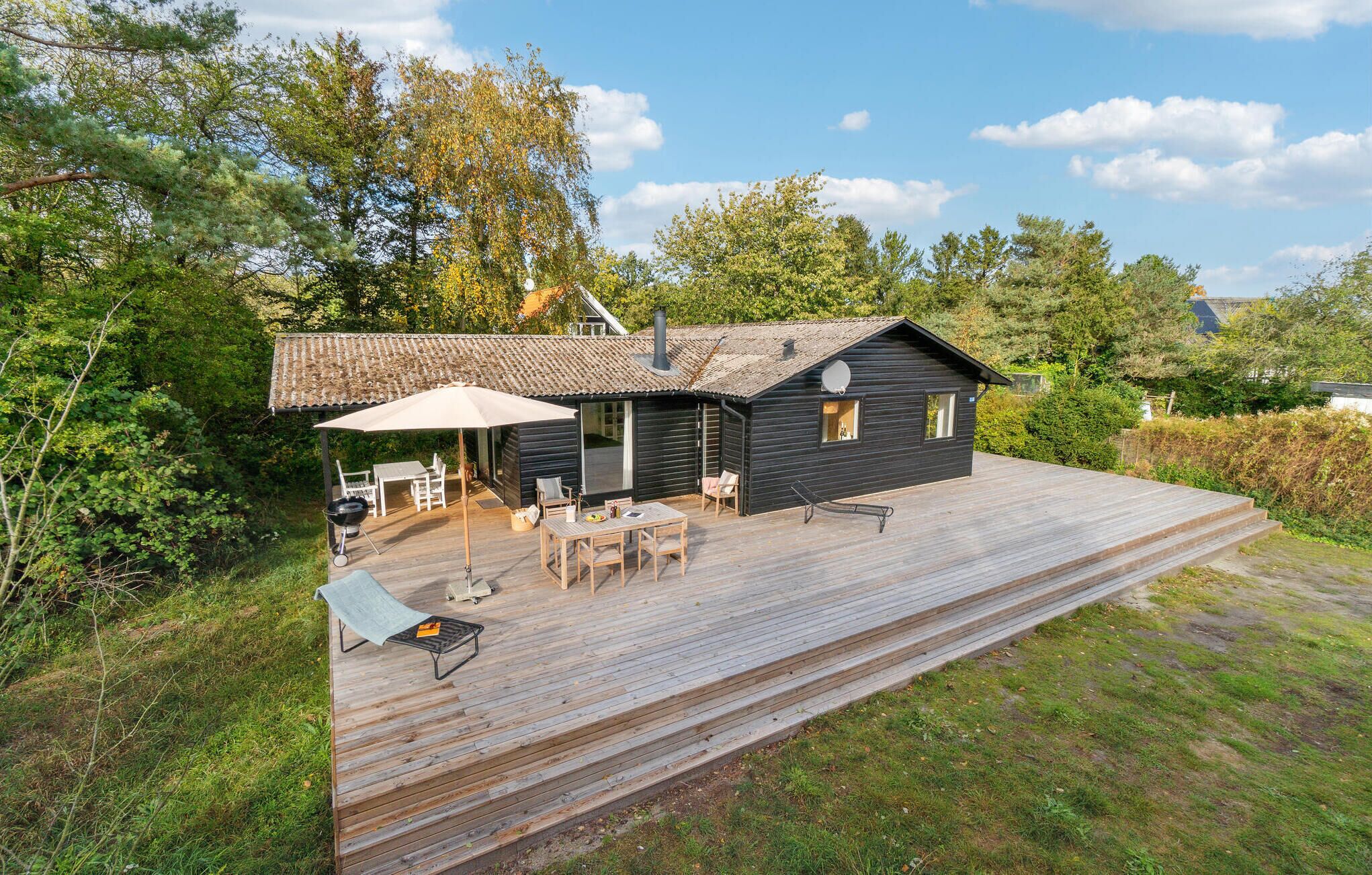 Une cabane dotée d’une terrasse, de meubles de jardin et d’un barbecue.