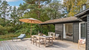 Een houten terras met een tafel, stoelen en een parasol.