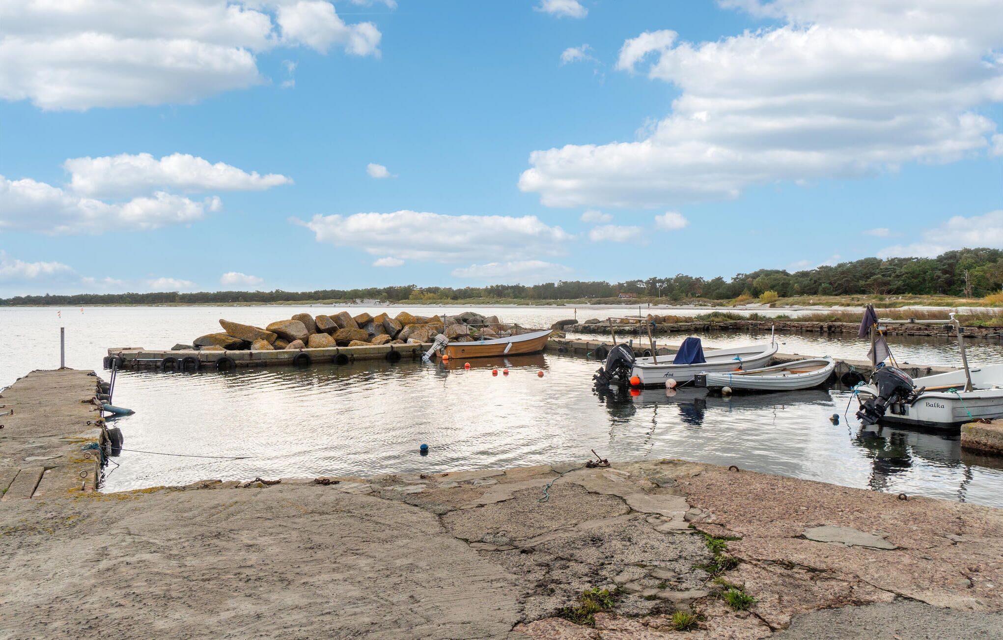 Un lago tranquilo con barcos amarrados en un muelle, rodeado de un paisaje natural.