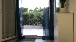 A bedroom with a bed, a sliding door leading to a patio, a potted plant, and a view of greenery outside. - Nouvel Grand Studio Agay vue mar Avec Jardin (Saint-Raphaël)