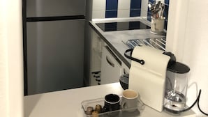 A compact kitchen with a refrigerator, microwave, and a coffee machine on the counter. - Nouvel Grand Studio Agay vue mar Avec Jardin (Saint-Raphaël)