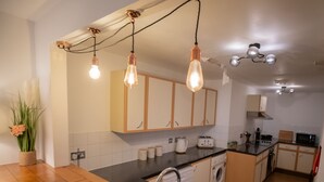 A modern kitchen with wooden cabinets, a black countertop, and a built-in washing machine. - Beautiful 1-bed Apartment in Manchester (Manchester)