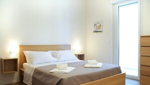 A neatly made bed with a wooden headboard, two bedside tables with lamps, and a small artwork on the wall. - Nice apartment in Pineto with swimming pool (Pineto)
