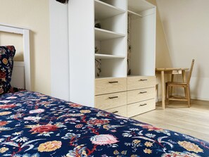 Ein Schlafzimmer mit Bett, Kleiderschrank, Schreibtisch und Stuhl.
