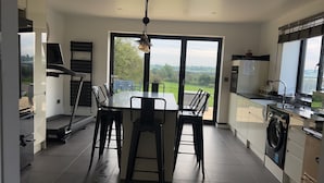 A modern kitchen with a dining area, large windows, and a view of the countryside. - Beautiful 3-bed Barn in Uttoxeter (Uttoxeter)
