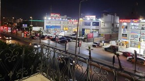 Vista nocturna de una zona comercial con escaparates iluminados, incluyendo una panadería y una farmacia.