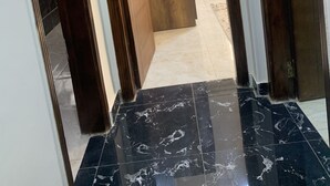 Un pasillo con piso de mármol que conduce a una habitación con una puerta de madera grande.