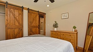 Un dormitorio con cama, armario de madera, cómoda y espejo.