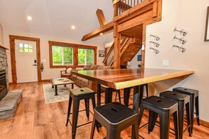 Una cocina amplia con una isla grande, taburetes de madera y una escalera que sube a un nivel superior.