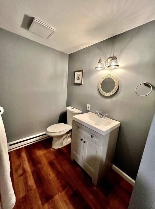 A bathroom with a toilet, sink, and mirror.