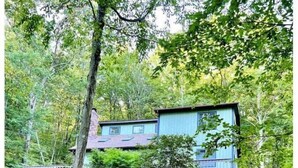 A two-story house with a blue exterior, surrounded by dense forest. - Retreat to Jackson's Ridge and enjoy the Poconos! (East Stroudsburg)