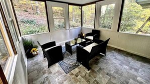 A covered patio with a table and chairs, large windows, and a view of trees. - Retreat to Jackson's Ridge and enjoy the Poconos! (East Stroudsburg)