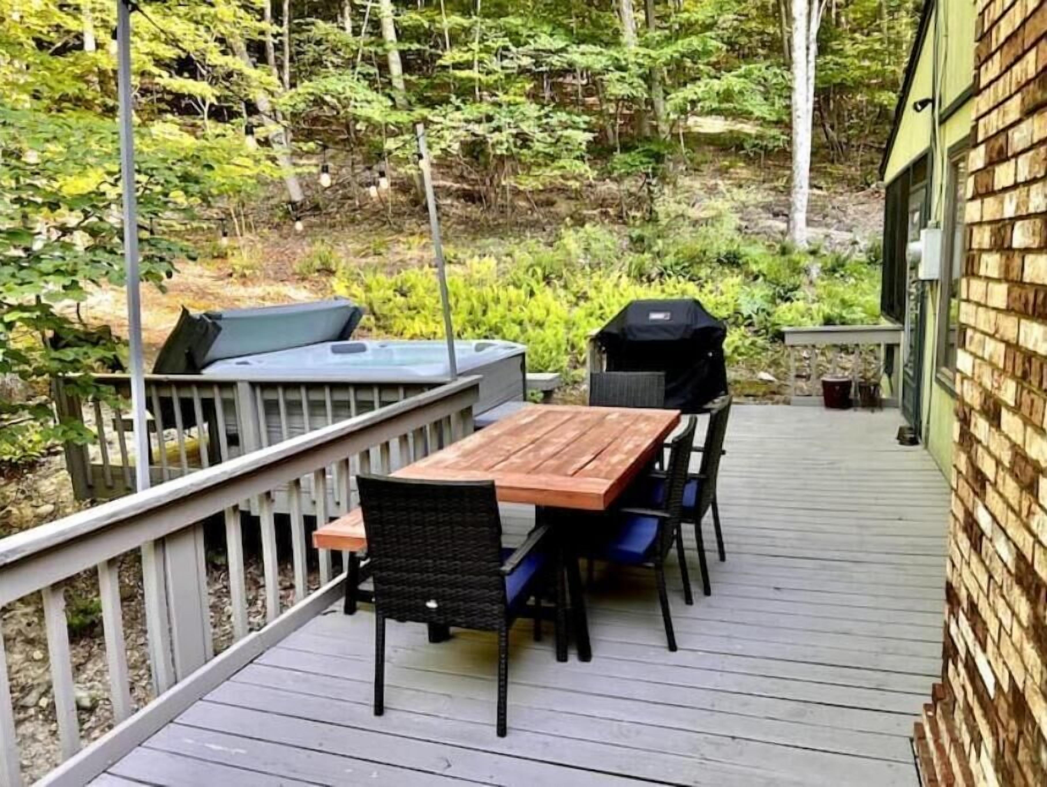 Une terrasse en bois avec une table et des chaises, un barbecue et un espace abrité.