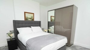 Un dormitorio moderno con una cama grande, un armario gris y un cuadro en la pared.