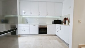 A modern kitchen with white cabinets, a built-in oven, a microwave, and a stainless steel sink. - Cozy apartment with Jacuzzi/ fast WIFI/PS5/huge pool and kids pool. Family place (CN)