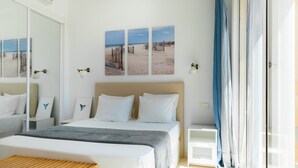 A hotel room with a large bed, a bedside table, a bench, and a view of the beach through the window. - Cozy apartment with Jacuzzi/ fast WIFI/PS5/huge pool and kids pool. Family place (CN)