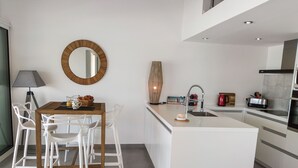 Une cuisine moderne avec un îlot central, des meubles blancs et un grand miroir rond accroché au mur.