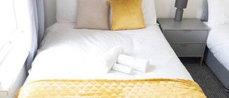 A hotel room with a bed, a nightstand, and a window.