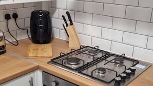 Cozinha compacta com fogão a gás, forno e máquina de café no balcão.