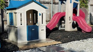 Ein Spielhäuschen mit blauem Dach und einer Rutsche.