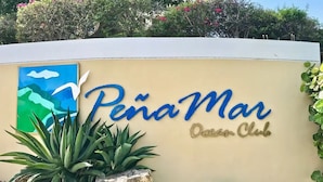 Une enseigne pour le Pena Mar Ocean Club, avec une peinture représentant un paysage côtier.