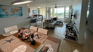 Un vaste espace de vie comprenant un coin repas, une cuisine et un balcon avec vue.