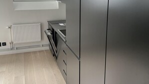 Une cuisine moderne dotée d’appareils électroménagers en acier inoxydable, d’une fenêtre avec stores et d’un four encastré.