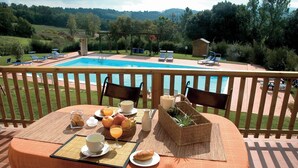 A table set with breakfast items, a pool, and a view of the countryside. - Apartment Flowers La Burraia (GAMBASSI TERME)