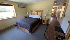 A bedroom with a wooden bed, a nightstand, a lamp, and a window.