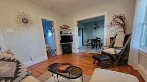 A living room with a fireplace, a dining area, and a seating area with a chair and ottoman.
