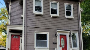A two-story house with a red front door, a red doorbell, and a mailbox.