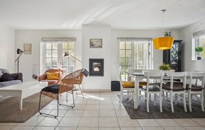 A spacious living area with a modern fireplace, a dining table with chairs, and a large window providing natural light. - Nice home in Gjern with WiFi (Gjern)