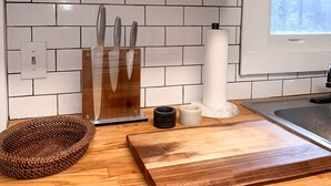 Una cocina con armarios blancos, tabla de cortar de madera, cesta tejida y bloque para cuchillos.