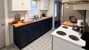 Una cocina moderna con armarios blancos, encimera de madera, estufa y una ventana con persianas.
