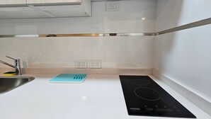 A modern kitchen with a stainless steel sink, a blue mat, and a black induction cooktop. - Tu Refugio en el Corazón de Montserrat (Buenos Aires)