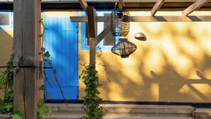 A wooden staircase with a blue door in the background, a hanging lantern, and greenery. - Lovely apartment at Solgaarden (9) Årsdale (Svaneke)