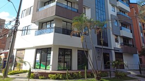 A multi-story building with balconies, a green entrance area, and signage for a business center.
