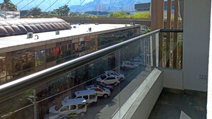 A balcony with a view of a cityscape, including a bridge and mountains.