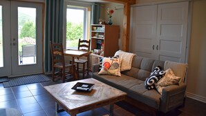 Una sala de estar con sofá, mesa de centro, estantería y comedor con sillas y mesa.