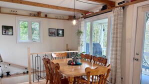 Un comedor con mesa y sillas de madera, ventanas amplias y vistas al exterior.