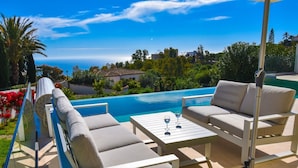 Ein Poolbereich mit zwei Liegestühlen, einem Tisch mit zwei Weingläsern und einem Pool mit Blick auf eine schöne Landschaft.