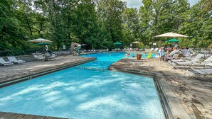 A swimming pool with lounge chairs and umbrellas, surrounded by trees. - PRIME location★Hot tub★Fire pit★Games★Sleeps 4 (Gatlinburg)
