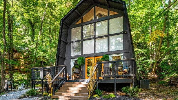 A modern wooden cabin with a large glass window, surrounded by a forest. - PRIME location★Hot tub★Fire pit★Games★Sleeps 4 (Gatlinburg)