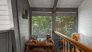 A wooden porch with a table holding a basket and a book, a wooden stool, and a wooden railing. - PRIME location★Hot tub★Fire pit★Games★Sleeps 4 (Gatlinburg)