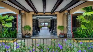 A covered outdoor area with a pathway, potted plants, and a railing. - Beachfront Luxury Condo with Direct Access to the Beach, 3 BR, 2 Baths, Balcony! (Jacó)