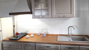A kitchen with white cabinets, a wooden countertop, a sink, and a range hood.