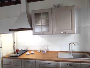 A kitchen with white cabinets, a wooden countertop, a sink, and a range hood. - Apartment with Garden View (GAMBASSI TERME)