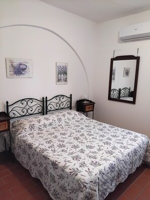 Une chambre à coucher comprenant un lit, une table de chevet, une commode, un miroir et un appareil de climatisation.