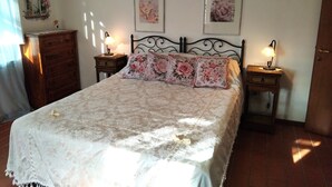 A bedroom with a bed, two bedside tables with lamps, a dresser, and two wall-mounted pictures. - Two Bedroom Apartment (GAMBASSI TERME)